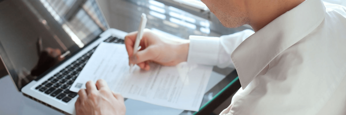 close up of business man with shirt and tie writing or signing a document on the desktop, form or content concept