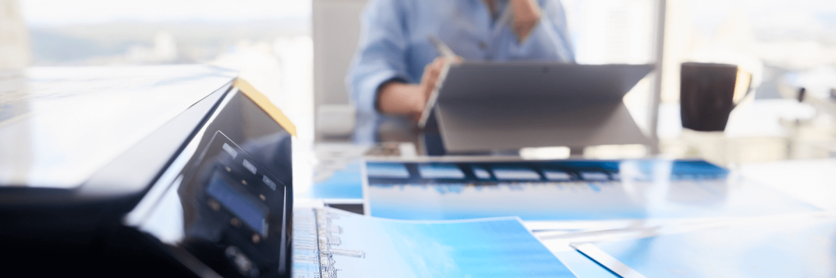 Girl with computer laptop for photo editing. Close-up of printer printing picture on photographic paper, small business office equipment or printer